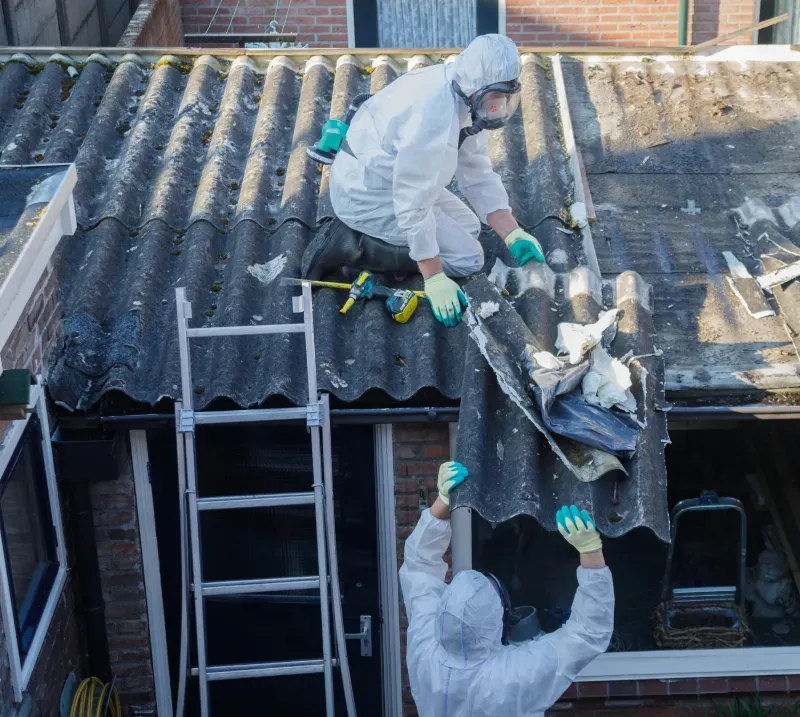 Asbestos removal workers removing corrugated roof sheets